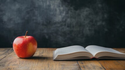 A teachers desk with an apple, chalkboard, and open book.