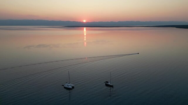 Small fishing boat going fishing at sunrise in the morning. Boat driving in calm sea off the coast of Silba, Croatia