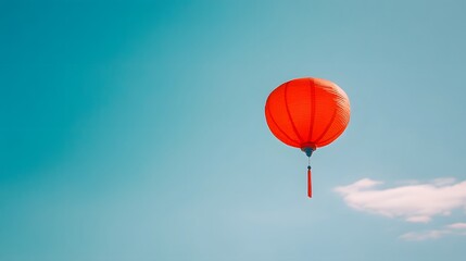 Fototapeta premium Bright red balloon floating against a clear blue sky, symbolizes freedom and joy, ideal for uplifting artistic projects.
