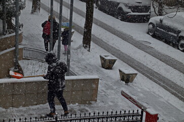 A young man carefully cleans the accumulated snow from a storm with strong winds and heavy snowfall in a residential area, Sofia, Bulgaria 