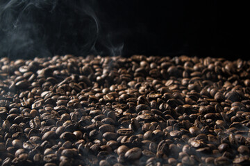 Fototapeta premium Freshly roasted coffee beans with smoke on black background