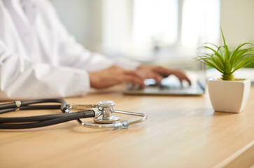 Close up of male doctor sitting at the desk on workplace in medical clinic with stethoscope in...