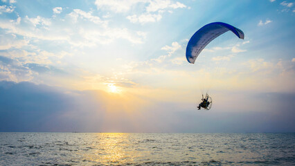Experience of paragliding over a tranquil ocean during sunset