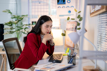 A woman in a red jacket is sitting at a desk with a keyboard