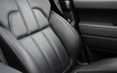 Obraz premium Car black leather interior. Part of black leather car seat details with white stitching. Interior of prestige car. Comfortable perforated leather seats. Perforated leather.
