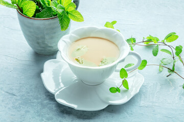 Mint tea. A cup of peppermint tea with fresh mint leaves, on a blue background