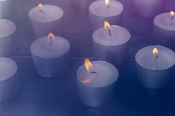 Tea light candles on a dark background, many lights in the dark, candlelight, toned image