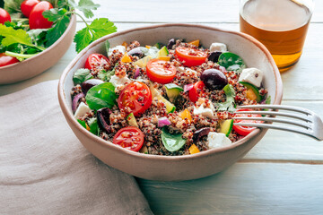 Quinoa salad, healthy Mediterranean lunch with fresh organic vegetables, cheese, and olives, with olive oil