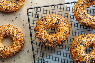 Bagels with sesame seeds, overhead flat lay shot on a cooling rack, with baking paper