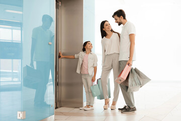 Family is exiting shopping mall with bags full of purchases.