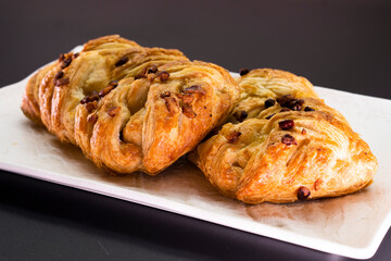 Fresh delicious puff pastry with maple syrup and nuts on black background