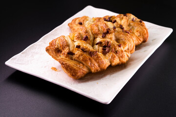 Fresh delicious puff pastry with maple syrup and nuts on black background