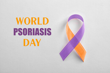 World Psoriasis Day. Orange-orchid awareness ribbon on white background, top view
