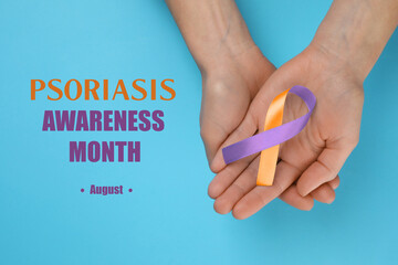 Psoriasis Awareness Month (August). Woman holding orange-orchid awareness ribbon on light blue background, top view