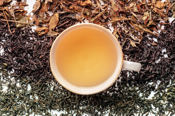 Loose tea leaves and a cup of tea. Black, green, and white teas in piles, overhead flat lay shot
