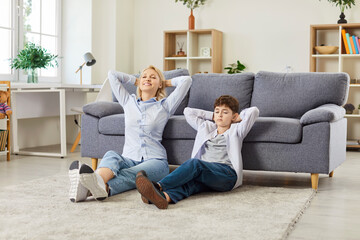 Obraz premium Loving mother, caring woman with little son floor sitting on new warm clean carpet near sofa enjoy time together at home weekend, two generations family love, rest and feel happy in comfortable room