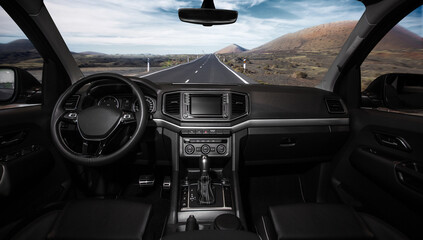 A car is driving down a road with a mountain in the background
