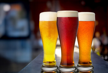 Three glasses of beer on a bar counter