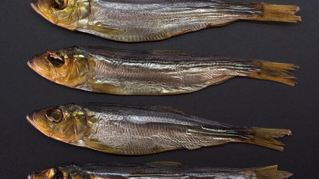 Hot smoked whole herrings on kitchen table. smoked fish isolated on a black background. Smoke
