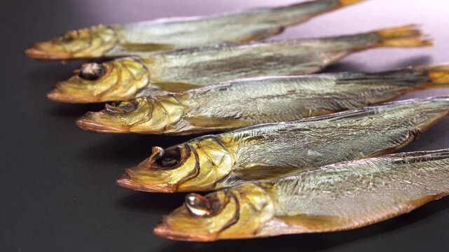 Hot smoked whole herrings on kitchen table. smoked fish isolated on a black background. Smoke