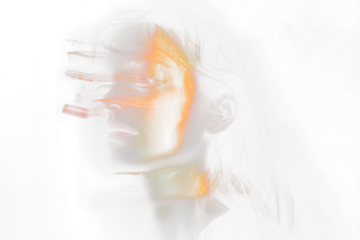Woman's face lit by orange light streaks.