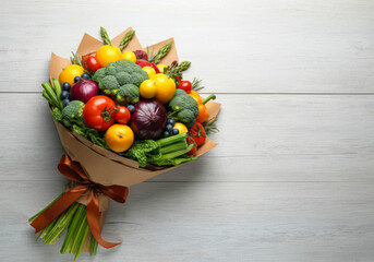 Colorful bouquet of fresh vegetables and fruits arranged in natural wrapper on a wooden surface showcasing healthy eating © Hanna