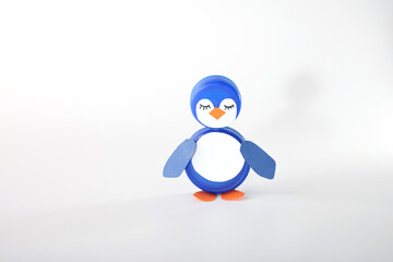 Repurposed blue plastic bottle caps, one forming a penguin with paper wings and feet. Great for eco-friendly initiatives, craft shops, and educational resources focusing on creative recycling
