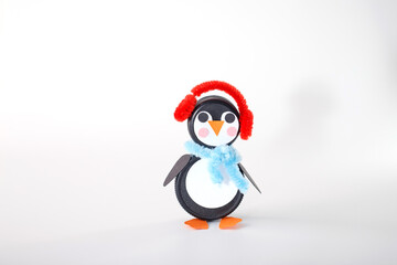 Black plastic bottle caps repurposed into a penguin with creative accessories. Ideal for art supplies, upcycling projects, and educational resources focused on fun, eco-friendly crafts for children,