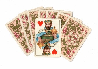 A fan of antique playing card backs with one card revealed.