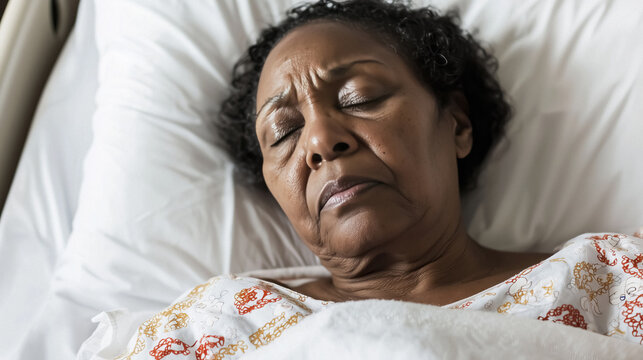 Senior black woman with serious expression in hospital bed resting and showing feelings of discomfort