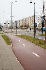 Urban street view of modern cityscape featuring bike lane, pedestrian crossing, apartments, traffic lights, cycling infrastructure, road signage, and urban living