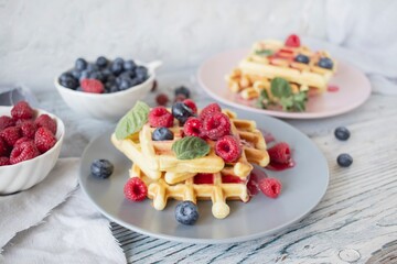 Belgian waffles with raspberries, blueberries and mint on a wooden background, homemade cakes, breakfast
