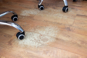 A section of laminate flooring with noticeable abrasions and traces of wear from an office chair on...