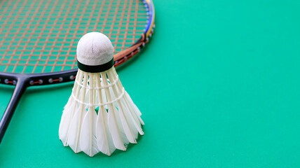 Badminton racket and white shuttlecock on green background