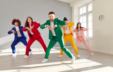 Fototapeta premium Group of energetic dancers rehearsing moves while learning new dance. Young people in bright colorful suits having fun and dancing together indoors. Disco party and active lifestyle concept.