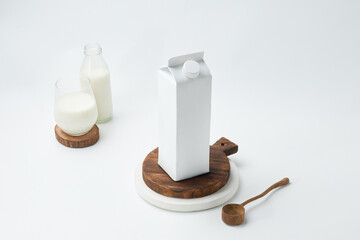 Milk Carton and Glass on Wooden Coaster With Rustic Spoon Displayed on Light Background