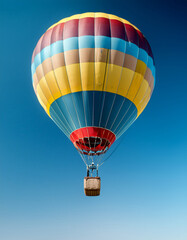 Fototapeta premium Close-up de un globo aerostatico de colores volando aislado sobre un cielo azul
