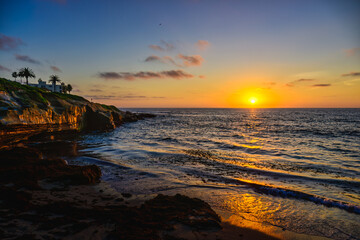Naklejka premium 2023-12-31 SUNSET IN LA JOLLA WITH A CALM PACIFIC OCEAN AND A REFLECTION WITH THE SHORELINE NEAR SAN DIEGO 