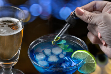 Pouring liquid into a vibrant blue cocktail glass