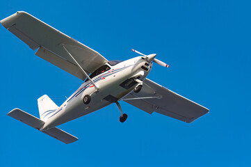 Compact aircraft gliding across brilliant azure sky, embodying aerial freedom with sunlight gleaming on wings