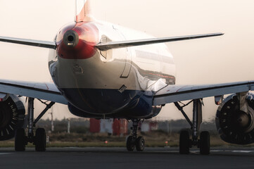 Naklejka premium Modern passenger airplane taxiing on the runway during a beautiful sunset, preparing for takeoff or after landing