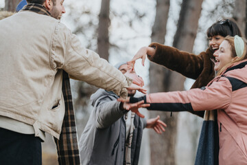 Friends standing outdoors during fall, engaging in a cheerful activity together, enjoying the season.