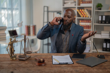 Serious african american lawyer is using smartphone having phone call conversation sitting at desk...