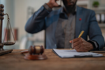 Lawyer reviewing and signing legal document while talking on the phone, with scales of justice and...