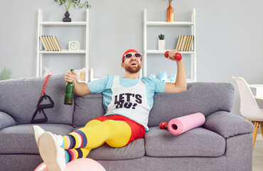 Lazy and happy man in a funny outfit lies on the couch, drinking alcohol during a supposed home...