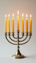 Golden Hanukkah candles glow brightly in a silver candelabrum on white background, candles, festive