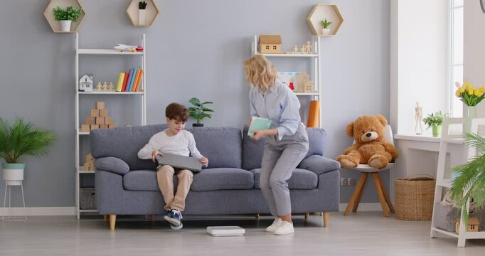 Loving, caring mother asks little child son, sitting on sofa with laptop, to stand on scales for weight check, writes down how much he has gained, gives him high five and hug. Kids, growth concept