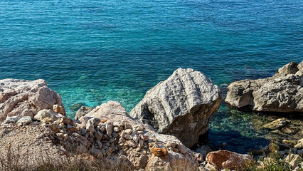 Coastal rocks by crystal-clear turquoise sea under the sun, travel vacation, Mediterranean serene...
