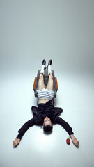 Bold and stylish dressed, male model lying upside down with legs elevated and rose lying nearby...