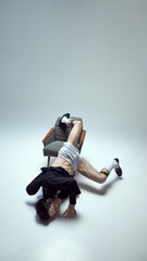 Creative young man, dance performer entangled in chair with expressive movement and artistic...